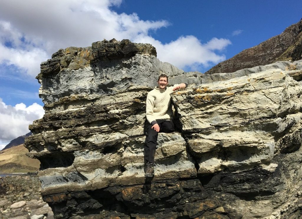 Woman sitting on top of a large, layered rock formation