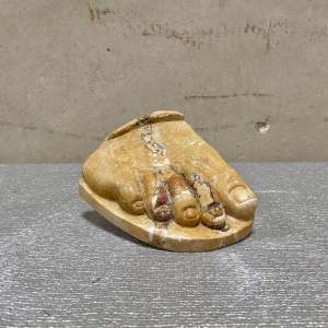 Sculpture of the front half of a foot in brown/yellow marble effect, showing cracks and damage to some of the toes
