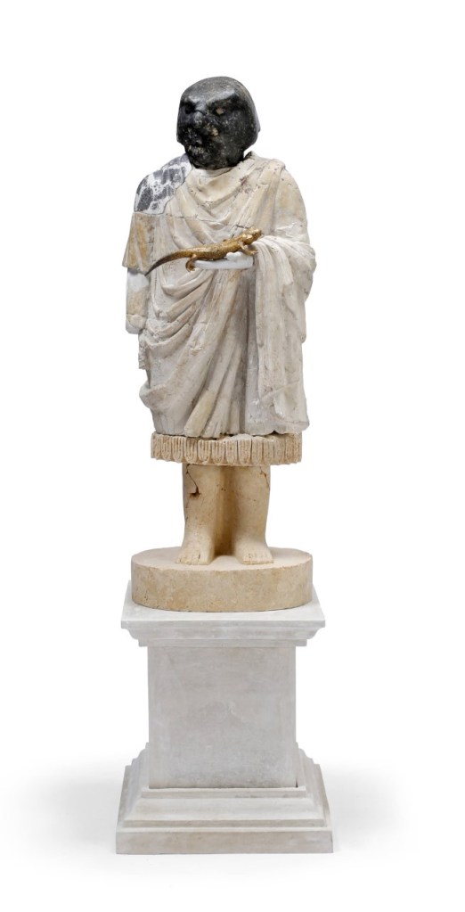 Statue of a robed figure standing on a plinth and holding a golden lizard-like reptile in one hand