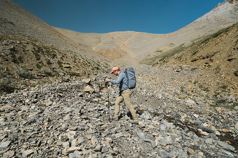 Dr Ross Anderson walks across a rocky, barren valley under a clear blue sky.